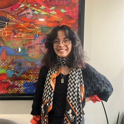 Kenza Talbi, alias Raven, souriante devant une grande toile colorée